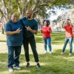 Group of adults engaging in fun team building activities in a sunny park, showcasing teamwork and diversity.